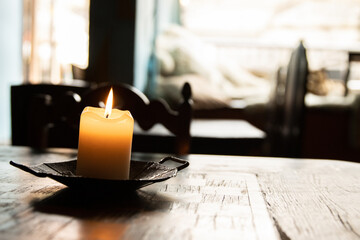 Lit candle on the wooden table with chessboard. Burning candle in the candleholder. Burning light....
