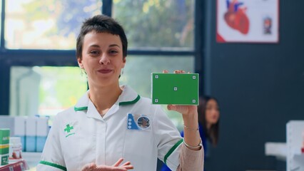 Portrait of joyful pharmacist in apothecary holding isolated packaged medical product. Smiling healthcare expert ready to provide medicinal services to shoppers, holding mockup medicament box