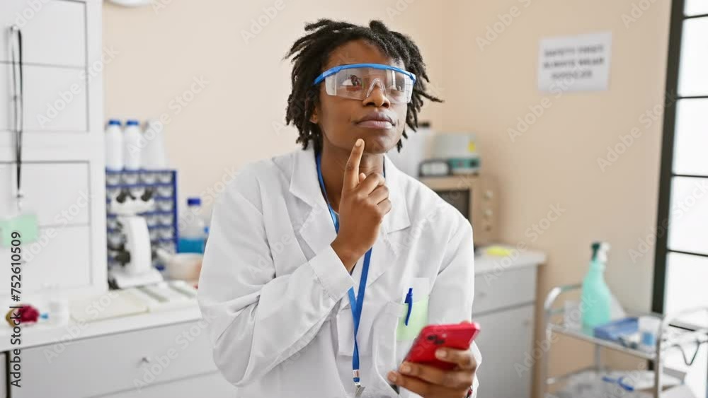 Sticker surprised young black woman with dreadlocks working on a smartphone in a lab, points finger with a h