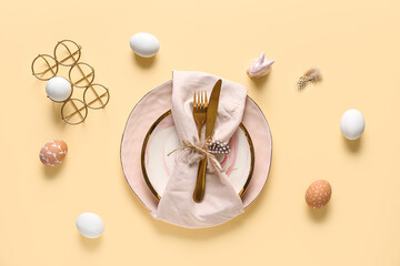 Beautiful table setting with Easter eggs and feathers on yellow background