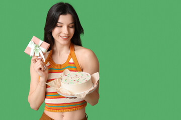 Beautiful young woman with sweet bento cake and gift box on green background. International Women's Day - obrazy, fototapety, plakaty