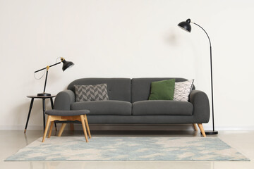 Comfortable sofa with footrest and lamps in living room