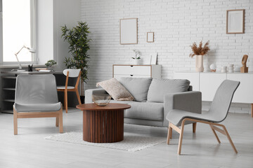 Stylish interior of living room with grey sofa and chairs