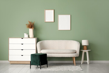 Stylish interior of living room with white sofa, pouf and chest of drawers