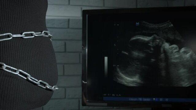 Chained pregnancy belly. A view of woman unchained her pregnant belly indoor. A concept of feeling pain and stress during pregnancy.