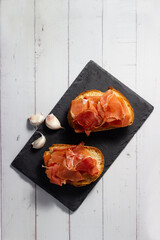 Top view of Iberian ham on toasted bread. Typical Spanish tapa. Mediterranean cuisine.