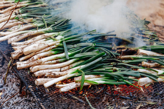 Piles of calcot, sweet onions typical Catalonia, Spain barbecue on the grill