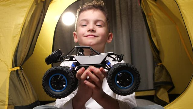 close-up portrait of a smiling boy with a rc toy truck in his hands