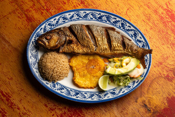Fried anchovy fish with coconut rice, patacon and vegetable salad