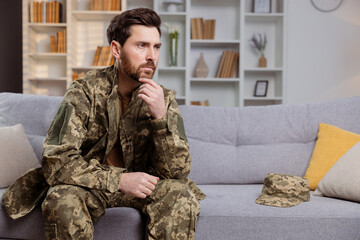 Fototapeta premium Man in uniform, returning home, battling depression. He is sitting on couch and looking away