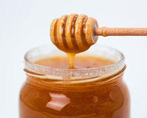 Honey in a glass jar with a special wooden spoon