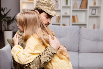 Happy family enjoying a military reunion. Dad in uniform, embracing his daughter in living room