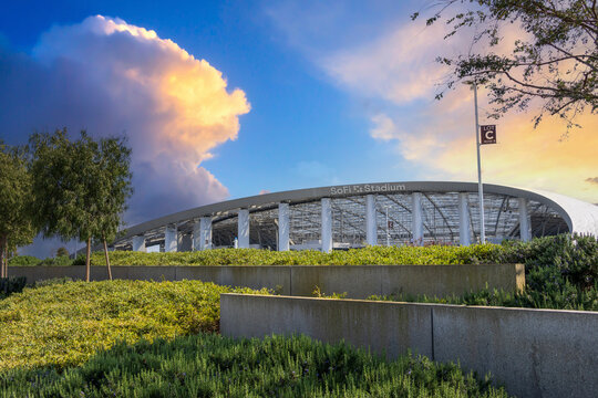 A beautiful spring landscape at SoFi Stadium with lush green palm trees and plants with powerful clouds at sunset in Inglewood California USA