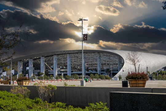 A beautiful spring landscape at SoFi Stadium with lush green palm trees and plants with powerful clouds at sunset in Inglewood California USA