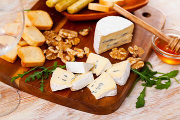 Fototapeta premium Sliced blue cheese served with walnut croutons and arugula at table