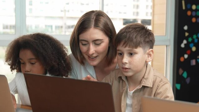Smart teacher teaching and looking student using laptop at classroom. Professional instructor explained about programing engineering code or prompt while studying and learning program. Erudition.