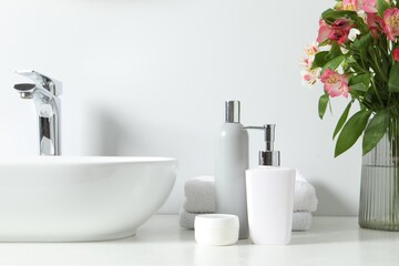 Vase with beautiful Alstroemeria flowers and toiletries near sink in bathroom - obrazy, fototapety, plakaty