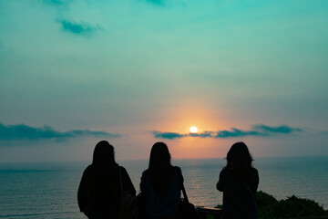 silhouette of three ladies looking at the horizon on the beach