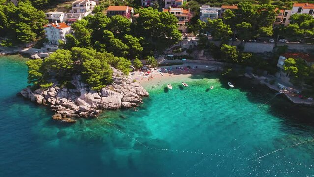 Aerial view of pebble beach with turquoise sea waters and sunbathers in Brela, Croatia. Popular tourist destination in summer.