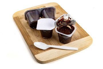 Chocolate grocery store pudding cups with a plastic spoon on a wooden board