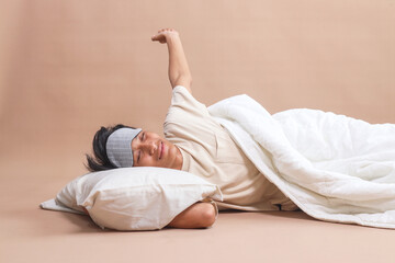 Young man with eye mask stretching his hands after wake up in the morning