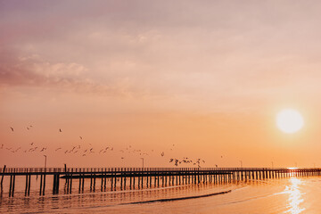 Fototapeta na wymiar Sunset sea view seascape orange clear sky with long bridge.