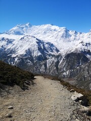 A rugged dirt path winds through towering snowy peaks, offering glimpses of majestic scenery and a challenging journey.