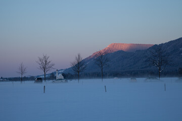 A pristine snowy field stretches out beneath a majestic mountain, creating a breathtaking winter landscape.