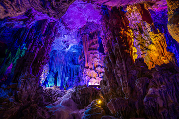 Inside the cave. Stalactites, stalagmites, coloured light. Beautiful background
