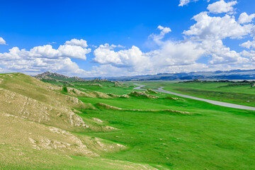 Green grass and mountains with river natural landscape in Xinjiang. Beautiful prairie landscape in summer.