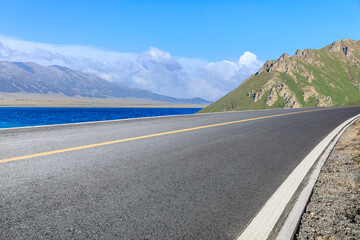 Asphalt highway and blue lake with mountain natural landscape under blue sky