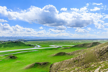 Fototapeta na wymiar Curved river and green grassland with mountain natural landscape in Xinjiang