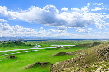 Naklejka premium Curved river and green grassland with mountain natural landscape in Xinjiang