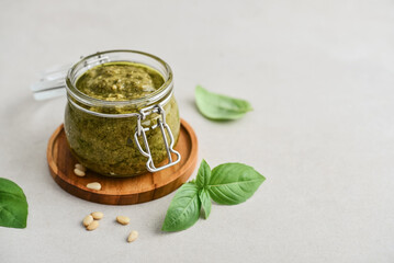 Sauce pesto in glass jar with fresh basil