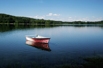 Fishing boat on the shore of a lake in the forest.
