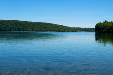 Beautiful lake with blue water and green forest on the horizon.