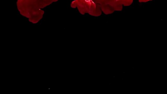 Slow motion of red drop in water.