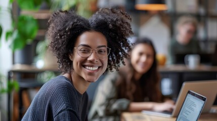 Smiling businesswoman and coworker working over laptop at creative office