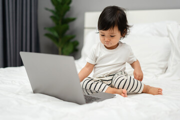 toddler baby watching laptop computer on bed
