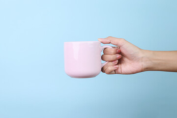 Obraz premium Hands Holding Ceramic Mug Isolated on Blue Background