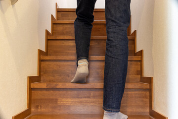 木の階段を上る人物の足を後ろから見上げる