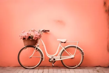Foto op Canvas A white bicycle with flowers near the peach-colored wall © Юлия Жигирь
