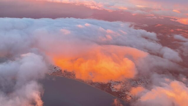 Cloudscape from above. Orange clouds over Almeria Coast, Spain, next to Mediterranean Sea. 4K 60FPS. Golden minute light. 4000m high. Pilot POV.