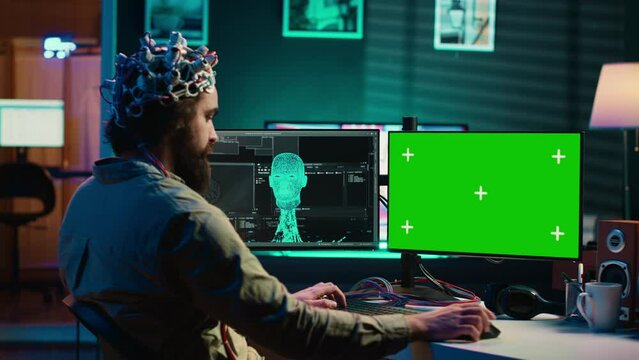 Developer using EEG headset, starting mind upload process using isolated screen desktop. Man using neuroscientific device to transfer consciousness into cyberspace with chroma key monitors, camera A