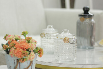 glass jar on a table with blurred flower foreground and background