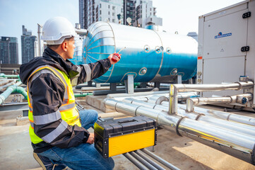 The image captures a skilled engineer inspecting a network of pipelines in a petrochemical...
