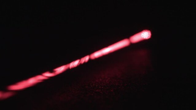 Long Red Laser Beam with Dust Particles on Black Background
