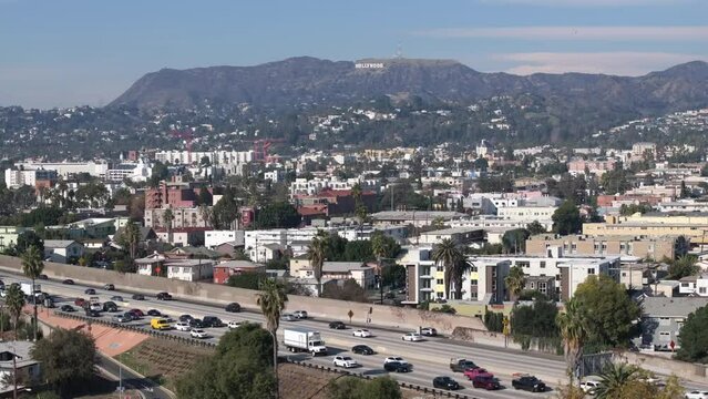 East Hollywood over 101 Freeway traffic, neighborhood and famous sign during day, aerial view