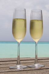 A vertical closeup of two champagne glasses against the beautiful turquoise sea The Maldives 