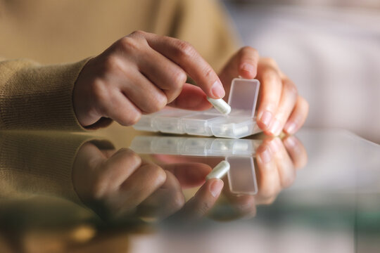 Closeup image of a woman holding and opening pills box
